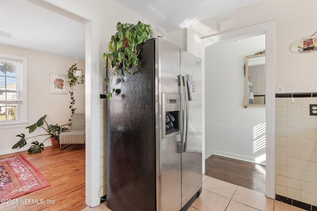 kitchen with light tile patterned flooring, stainless steel fridge with ice dispenser, and tile walls