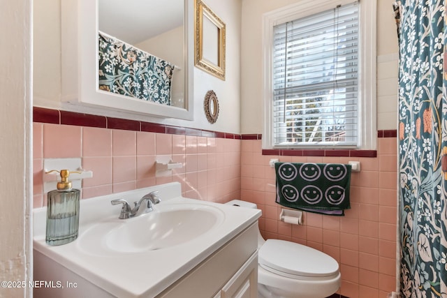 bathroom featuring vanity, toilet, and tile walls