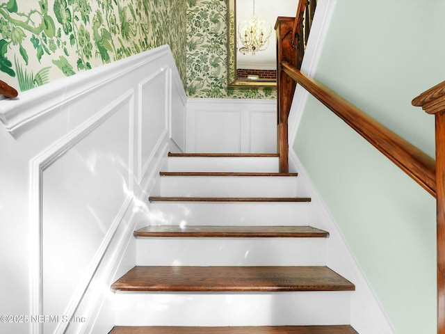 stairway featuring a notable chandelier