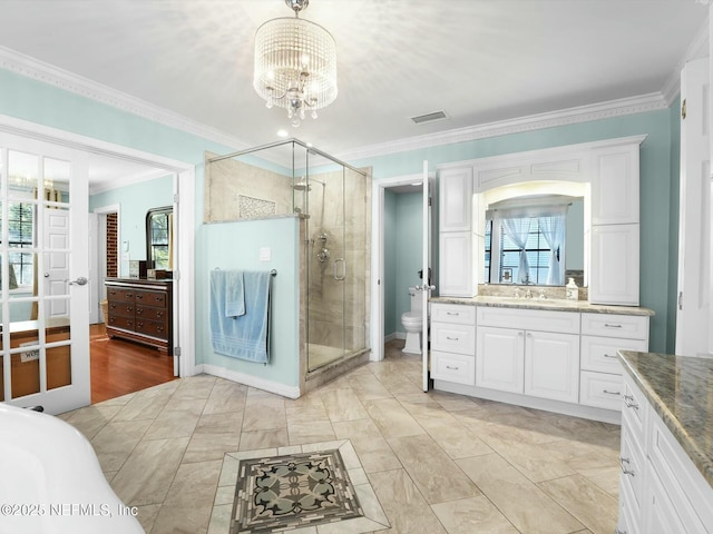 bathroom featuring toilet, vanity, ornamental molding, a shower with shower door, and an inviting chandelier