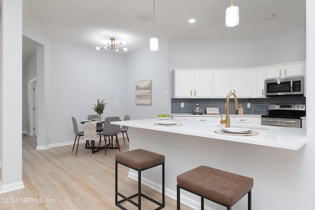 kitchen featuring a kitchen bar, pendant lighting, stainless steel appliances, and an inviting chandelier