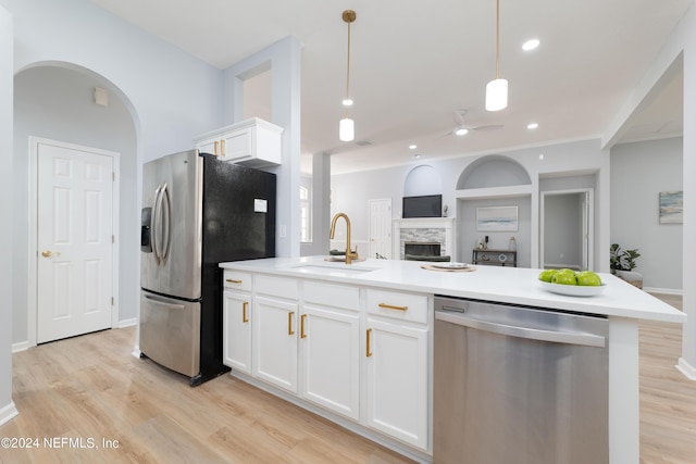 kitchen featuring appliances with stainless steel finishes, sink, a center island with sink, white cabinets, and hanging light fixtures