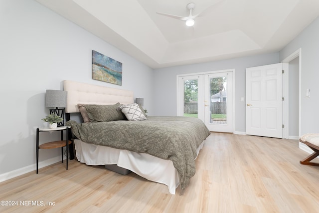 bedroom featuring access to outside, a raised ceiling, ceiling fan, and light hardwood / wood-style flooring