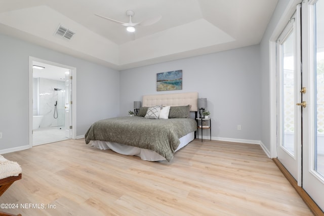 bedroom with a raised ceiling, ceiling fan, light hardwood / wood-style flooring, and ensuite bathroom