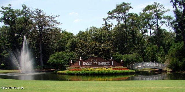 community / neighborhood sign with a lawn and a water view