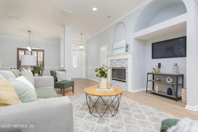 living room featuring crown molding, a fireplace, and wood-type flooring