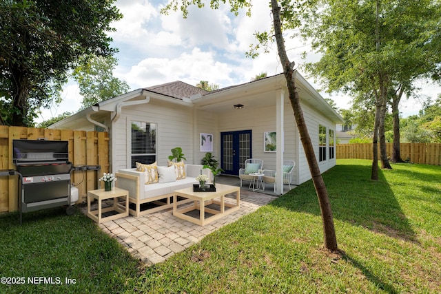 rear view of house featuring a lawn, an outdoor living space, french doors, and a patio