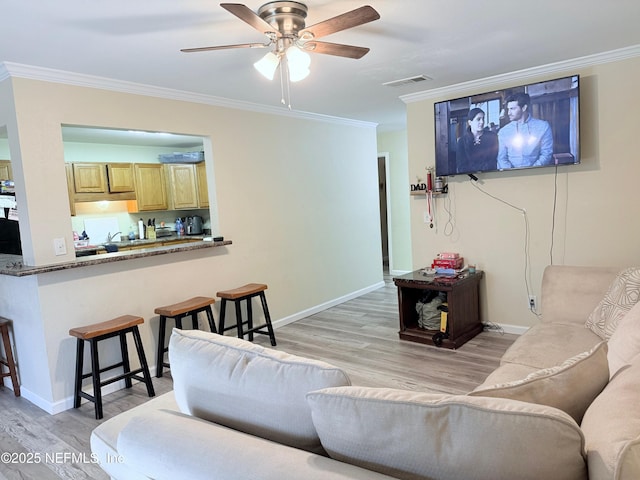 living room with crown molding, ceiling fan, and light wood-type flooring