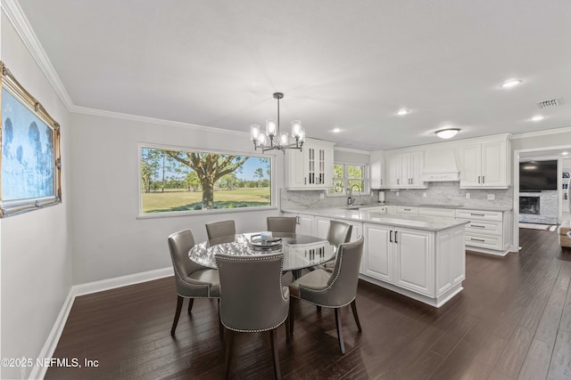 dining space featuring dark hardwood / wood-style flooring, crown molding, sink, and a chandelier