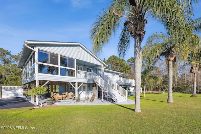 rear view of property with outdoor lounge area, a patio, a sunroom, and a lawn