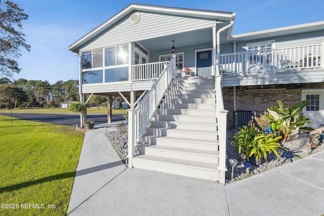 view of front facade with a sunroom, a porch, and a front yard