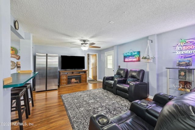 living room with ceiling fan, wood-type flooring, and a textured ceiling