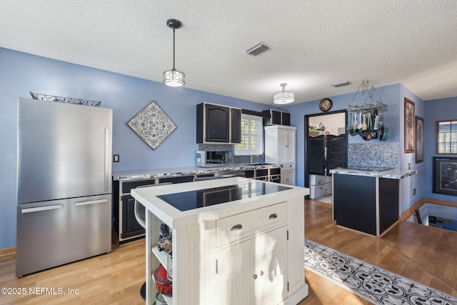 kitchen featuring stainless steel fridge, a textured ceiling, pendant lighting, a center island, and light hardwood / wood-style floors