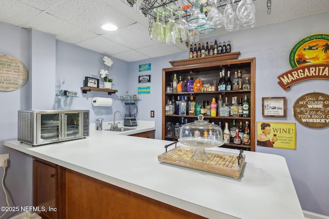 bar featuring a paneled ceiling and sink