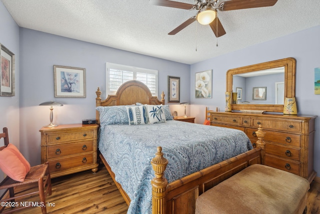 bedroom with ceiling fan, hardwood / wood-style floors, and a textured ceiling