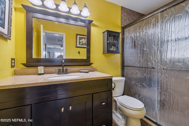 bathroom with an enclosed shower, vanity, toilet, and ceiling fan