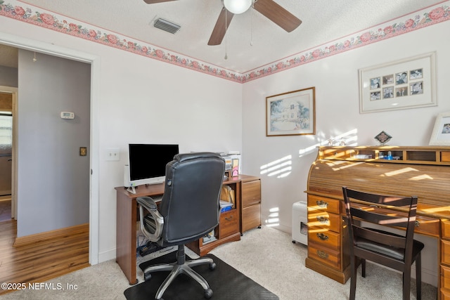 carpeted office featuring a textured ceiling and ceiling fan