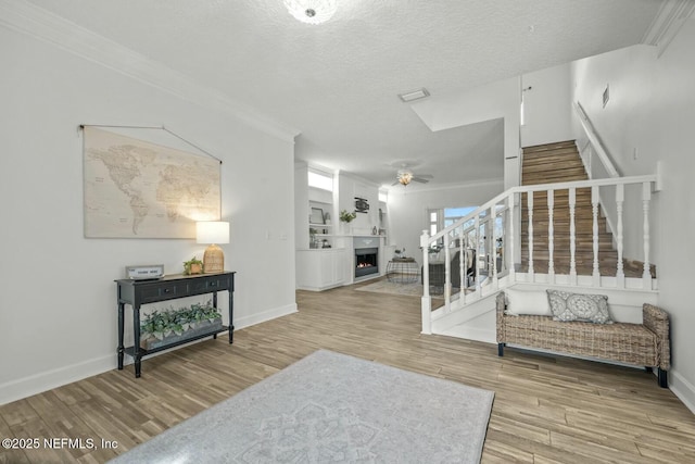 interior space with ornamental molding, a textured ceiling, and light hardwood / wood-style flooring