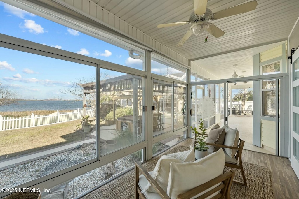 sunroom / solarium featuring a water view and ceiling fan