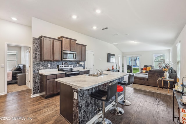 kitchen with lofted ceiling, a center island with sink, sink, dark hardwood / wood-style floors, and stainless steel appliances