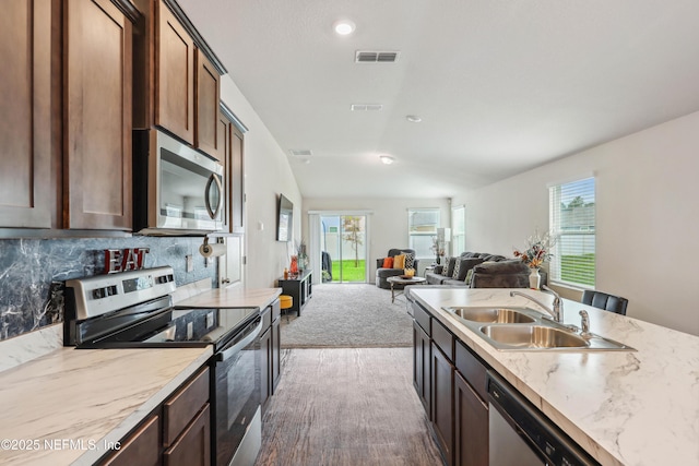 kitchen with appliances with stainless steel finishes, dark carpet, dark brown cabinets, and sink