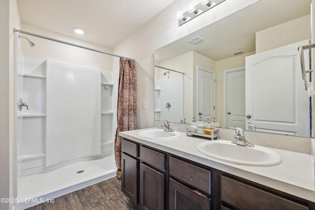 bathroom featuring vanity, wood-type flooring, a textured ceiling, and walk in shower