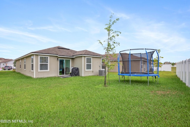 back of house featuring a lawn, cooling unit, and a trampoline