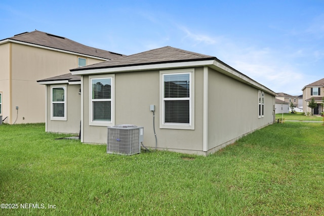 rear view of house featuring a lawn and central AC