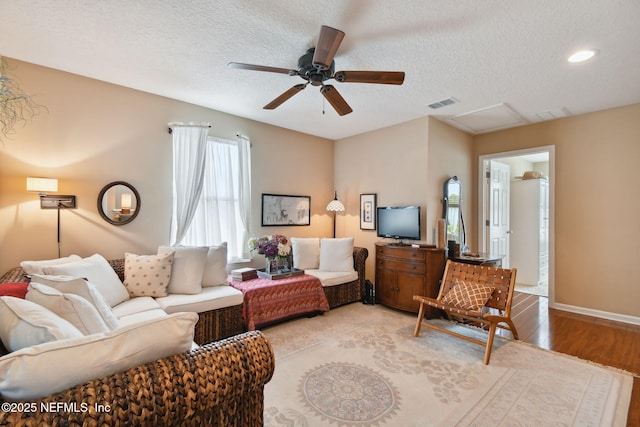 living room with a textured ceiling, light hardwood / wood-style floors, and ceiling fan