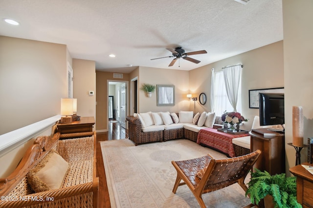 living room with hardwood / wood-style floors, a textured ceiling, and ceiling fan