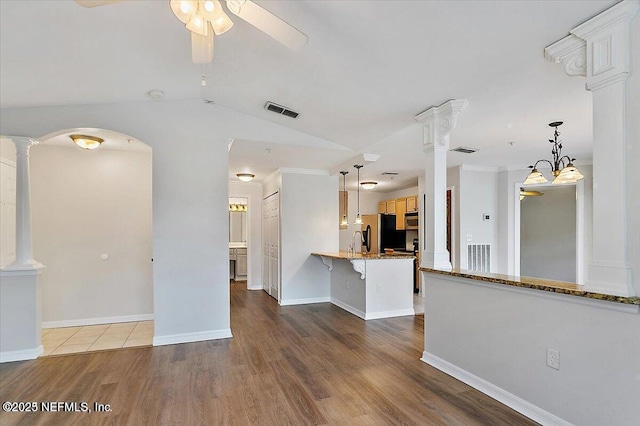 unfurnished living room with sink, light wood-type flooring, vaulted ceiling, ceiling fan with notable chandelier, and ornamental molding