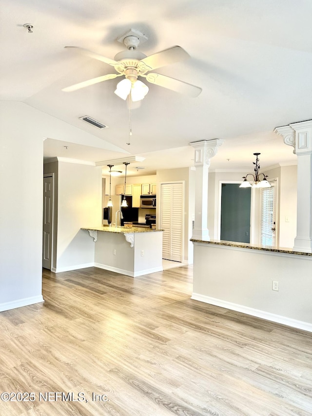 unfurnished living room with ornate columns, lofted ceiling, light hardwood / wood-style flooring, and ceiling fan with notable chandelier