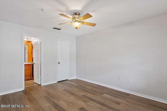 unfurnished bedroom featuring a closet, dark hardwood / wood-style floors, ensuite bath, and ceiling fan