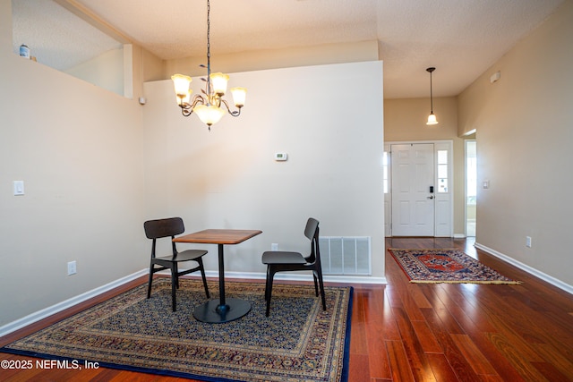 dining space with dark wood-type flooring and a chandelier