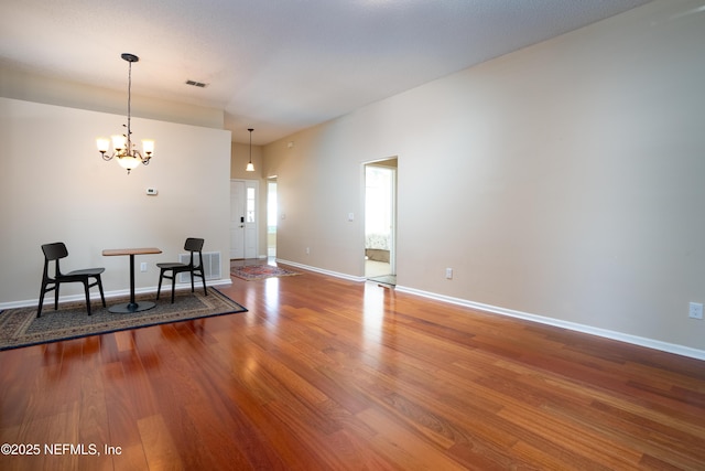 dining space with baseboards, wood finished floors, visible vents, and an inviting chandelier