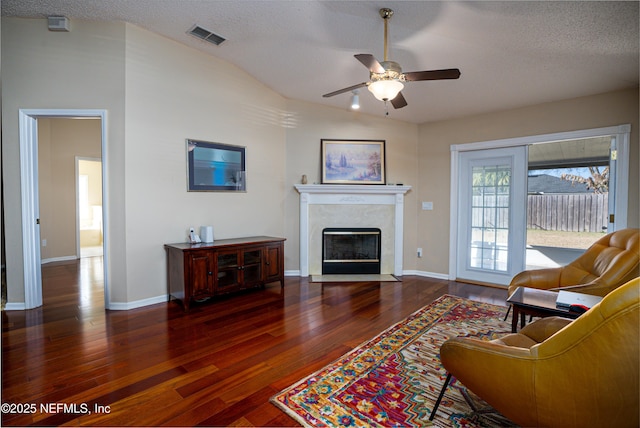 living room with dark hardwood / wood-style flooring, a textured ceiling, a premium fireplace, and ceiling fan