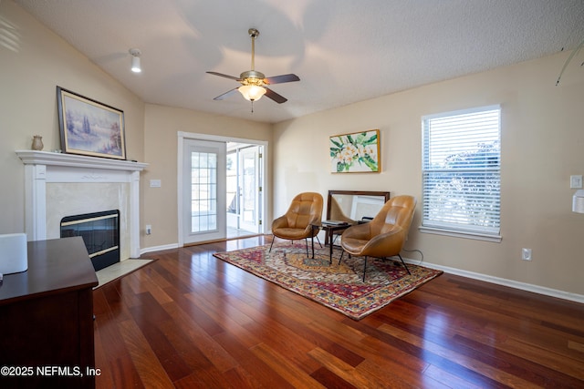 living area featuring dark hardwood / wood-style flooring, a textured ceiling, ceiling fan, and a high end fireplace