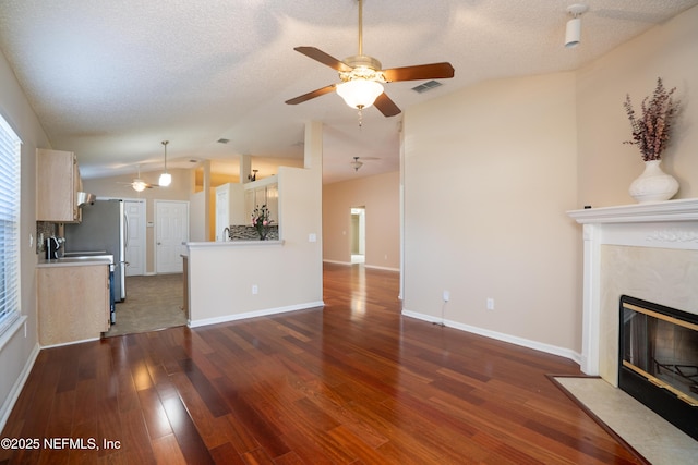 unfurnished living room featuring dark wood-type flooring, lofted ceiling, a fireplace, and a textured ceiling