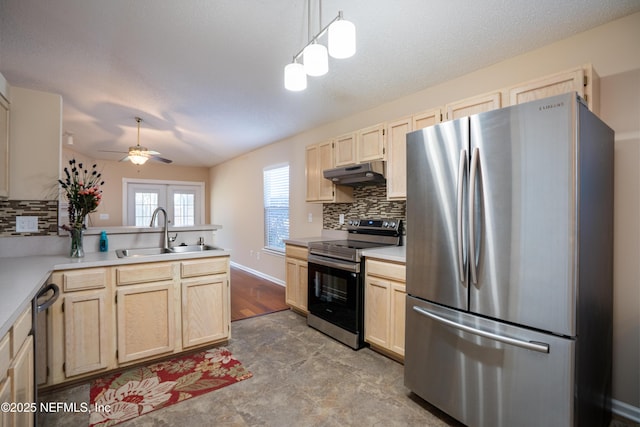 kitchen featuring appliances with stainless steel finishes, a peninsula, under cabinet range hood, light brown cabinets, and a sink