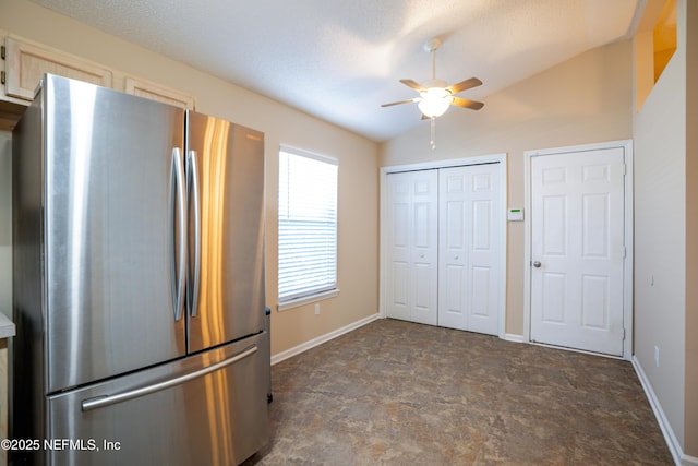 unfurnished bedroom with lofted ceiling, stone finish flooring, baseboards, and freestanding refrigerator