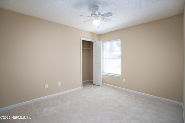 unfurnished bedroom featuring a closet, light carpet, ceiling fan, a textured ceiling, and baseboards