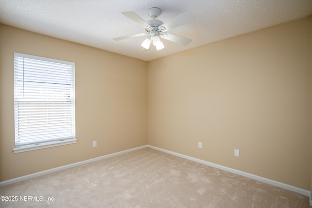 empty room featuring ceiling fan, baseboards, a textured ceiling, and light colored carpet