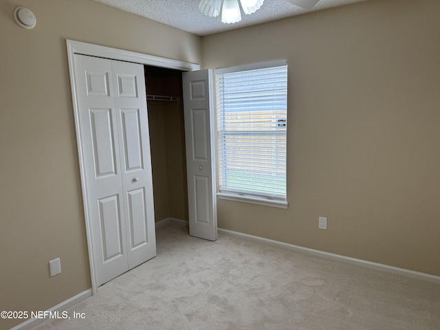 unfurnished bedroom with a textured ceiling, a closet, carpet flooring, and baseboards