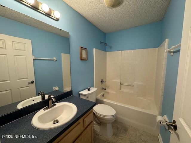 full bath with a textured ceiling, toilet, vanity, bathing tub / shower combination, and tile patterned floors