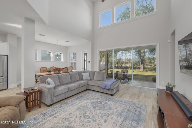 living room with light hardwood / wood-style flooring and a towering ceiling