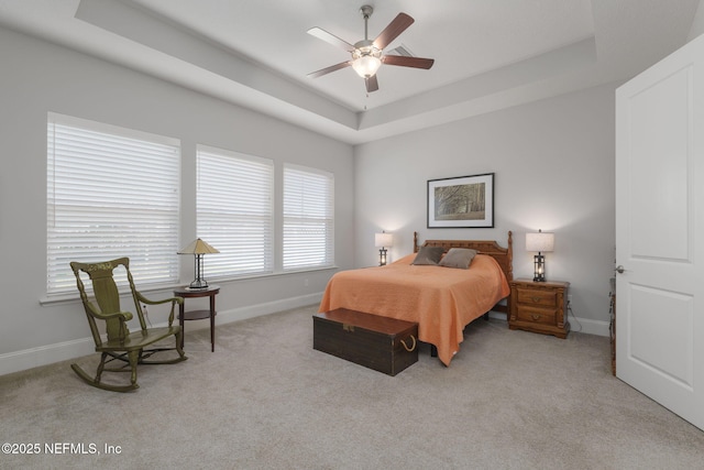 bedroom featuring ceiling fan, a raised ceiling, and light carpet