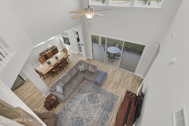 living room featuring visible vents, a high ceiling, ceiling fan, wood finished floors, and baseboards