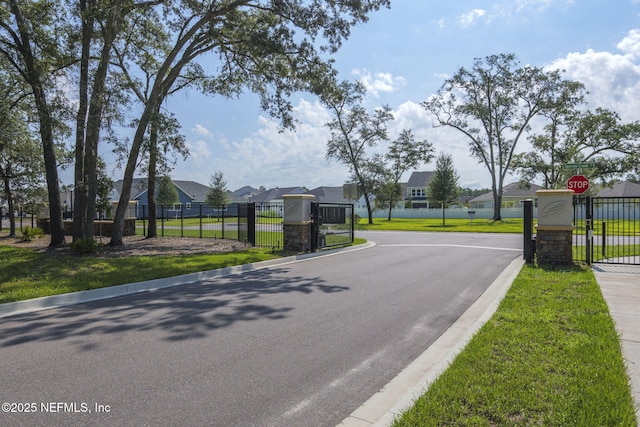 view of road featuring a gated entry, traffic signs, a gate, and a residential view