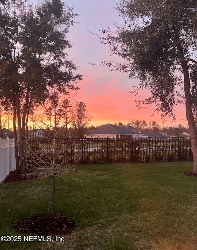 yard at dusk featuring fence