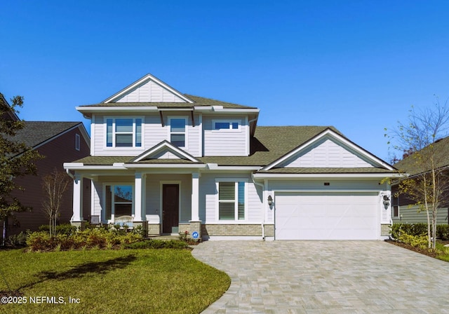 view of front of house with a porch, a garage, brick siding, decorative driveway, and a front yard